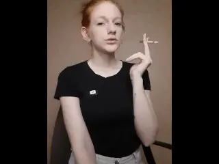 Redhead Girl Smokes a Cigarette, Hair is Gathered in a Bun