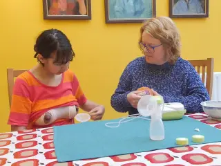 Old woman teaching young woman to pump breast milk