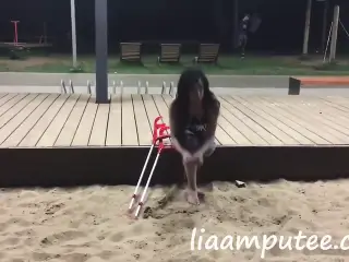 Amputee woman with crutches on the beach