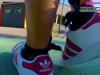 Girl in red Adidas Superstars does shoeplay, dipping fishnet socks